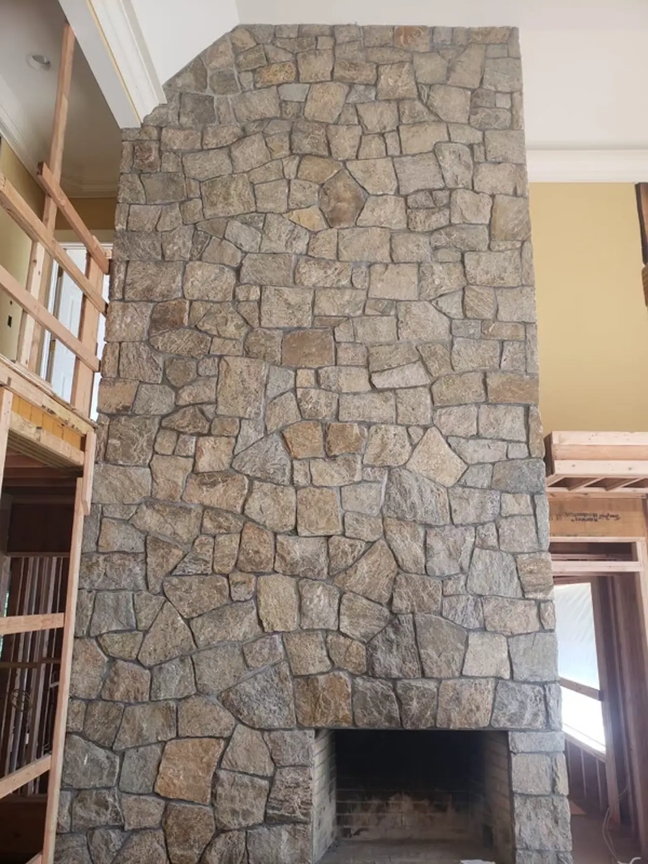 Floor-to-ceiling natural fieldstone fireplace rising two stories as the focal point of an open-plan great room