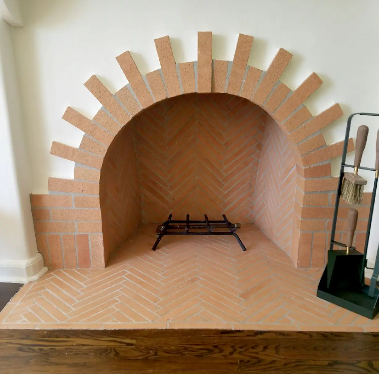 Spanish-style indoor fireplace with a radiating voussoir brick arch, herringbone firebox, and herringbone brick hearth